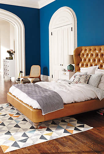 Blue bedroom with brown tufted leather headboard