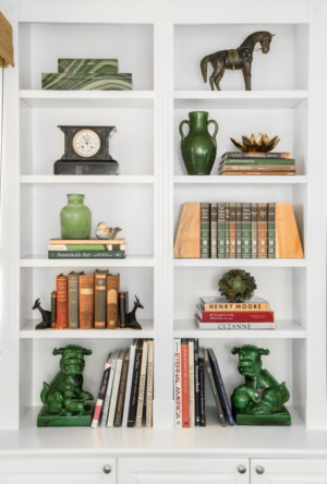 Bookcases with green objects, including Foo Dogs