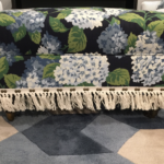 Rectangular ottoman upholstered in blue floral fabric with fringe trim
