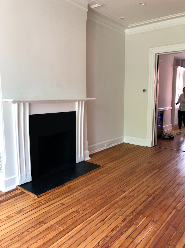 Empty Victorian living room with white walls and hardwood floors