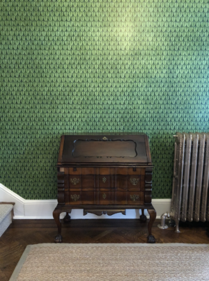 Green wallpaper behind an antique secretary
