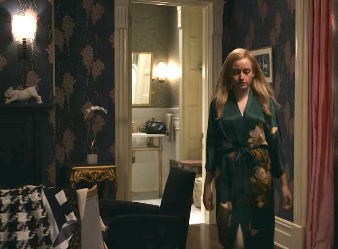 Woman in robe walking out of bathroom into fancy bedroom