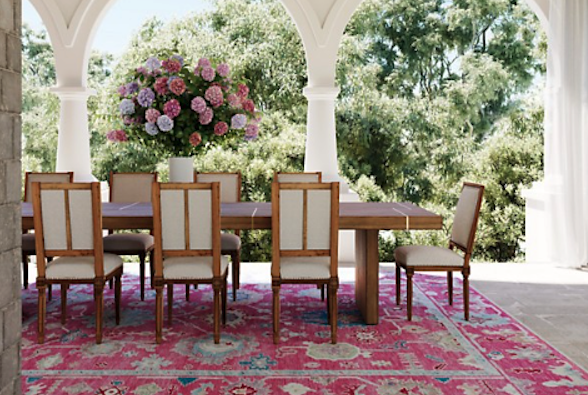 Outdoor dining space with bright pink Oriental rug