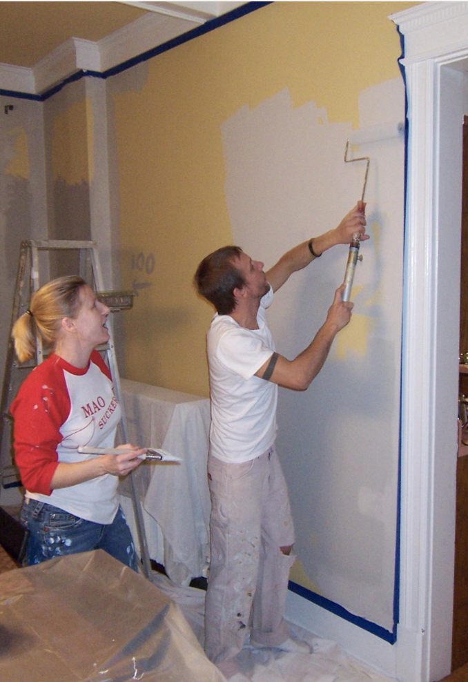 Man and woman painting a wall with roller