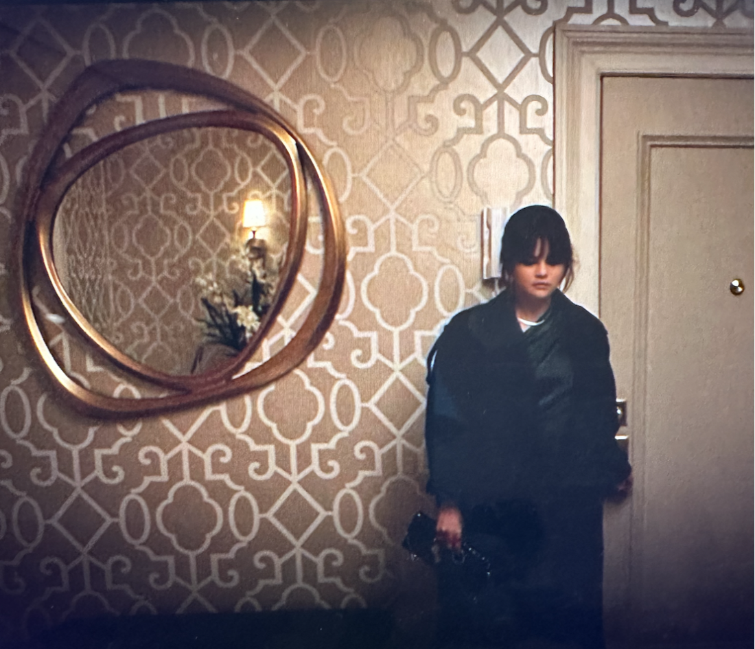 Woman in a foyer with horrible white on beige patterned wallpaper