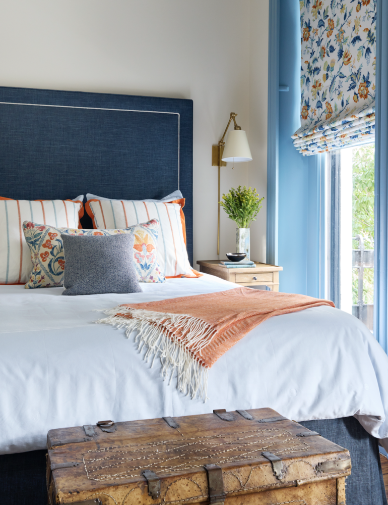 Cozy bedroom with blue headboard and floral Roman shade