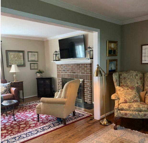 View into a somber room with a red brick fireplace from a sage green living room