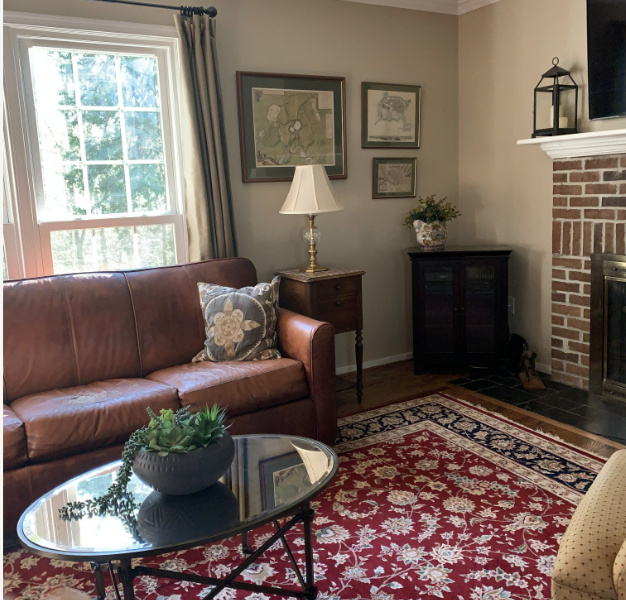Family room with brick fireplace, brown leather sofa and dark Oriental rug
