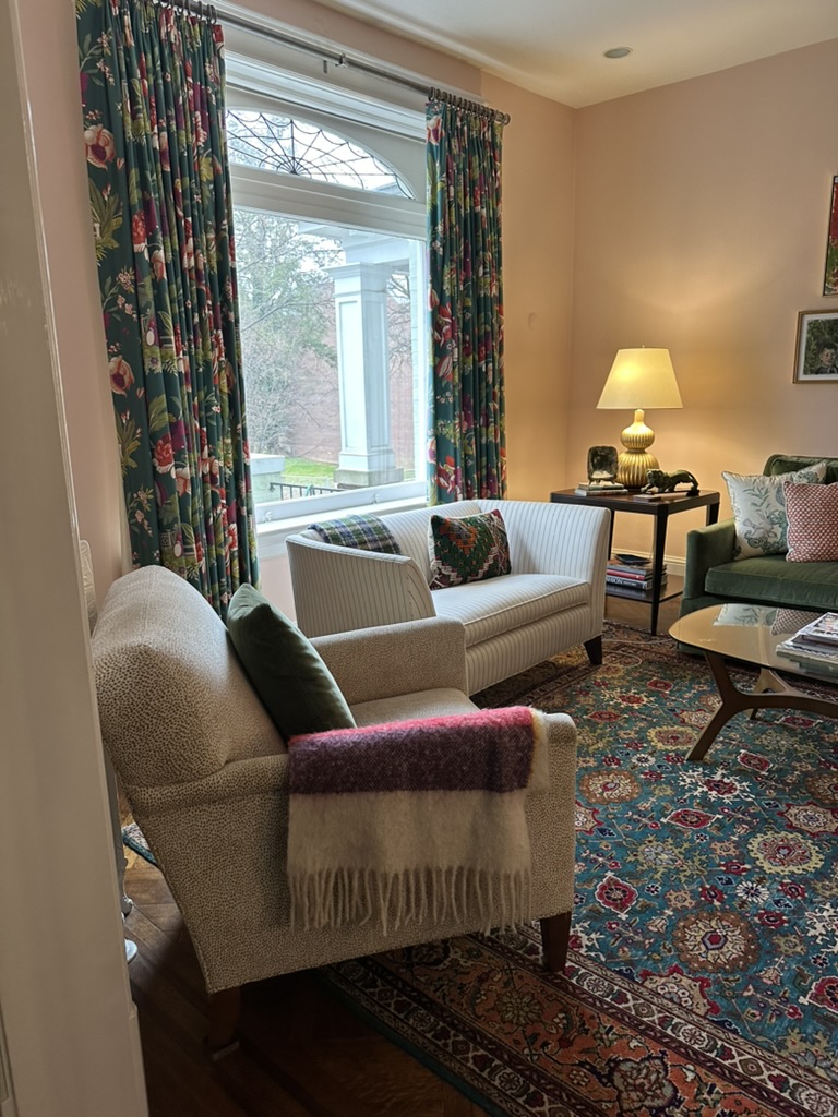 Small white striped sofa in front of large window with drapes