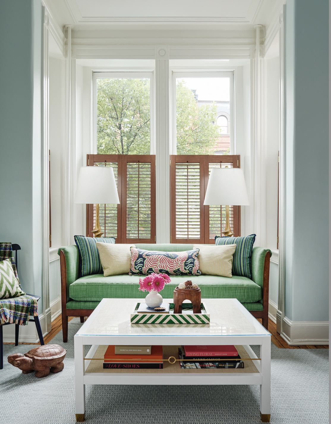 Green sofa in bay window with shutters