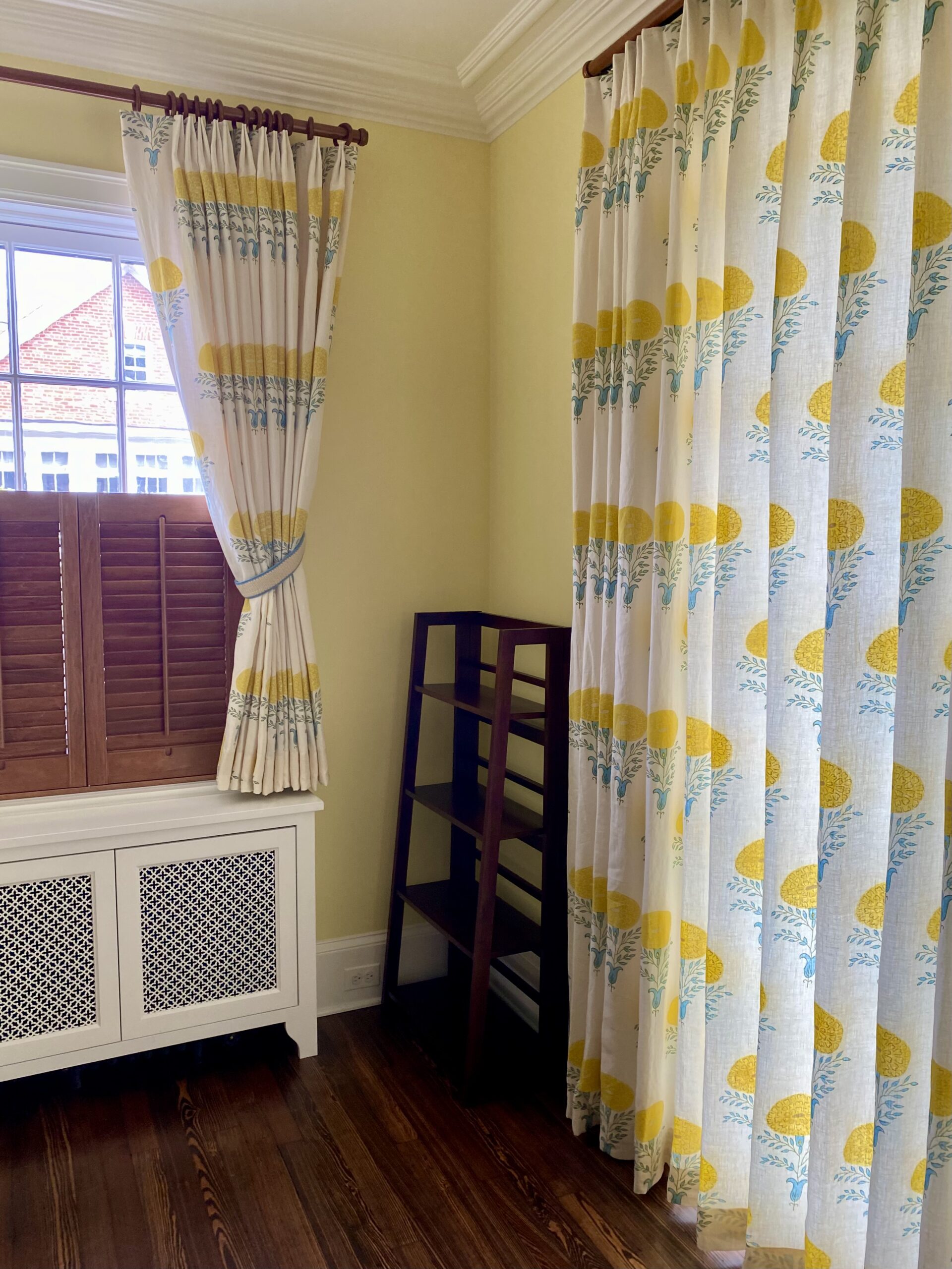 Yellow room with yellow and blue floral curtains and drapes.