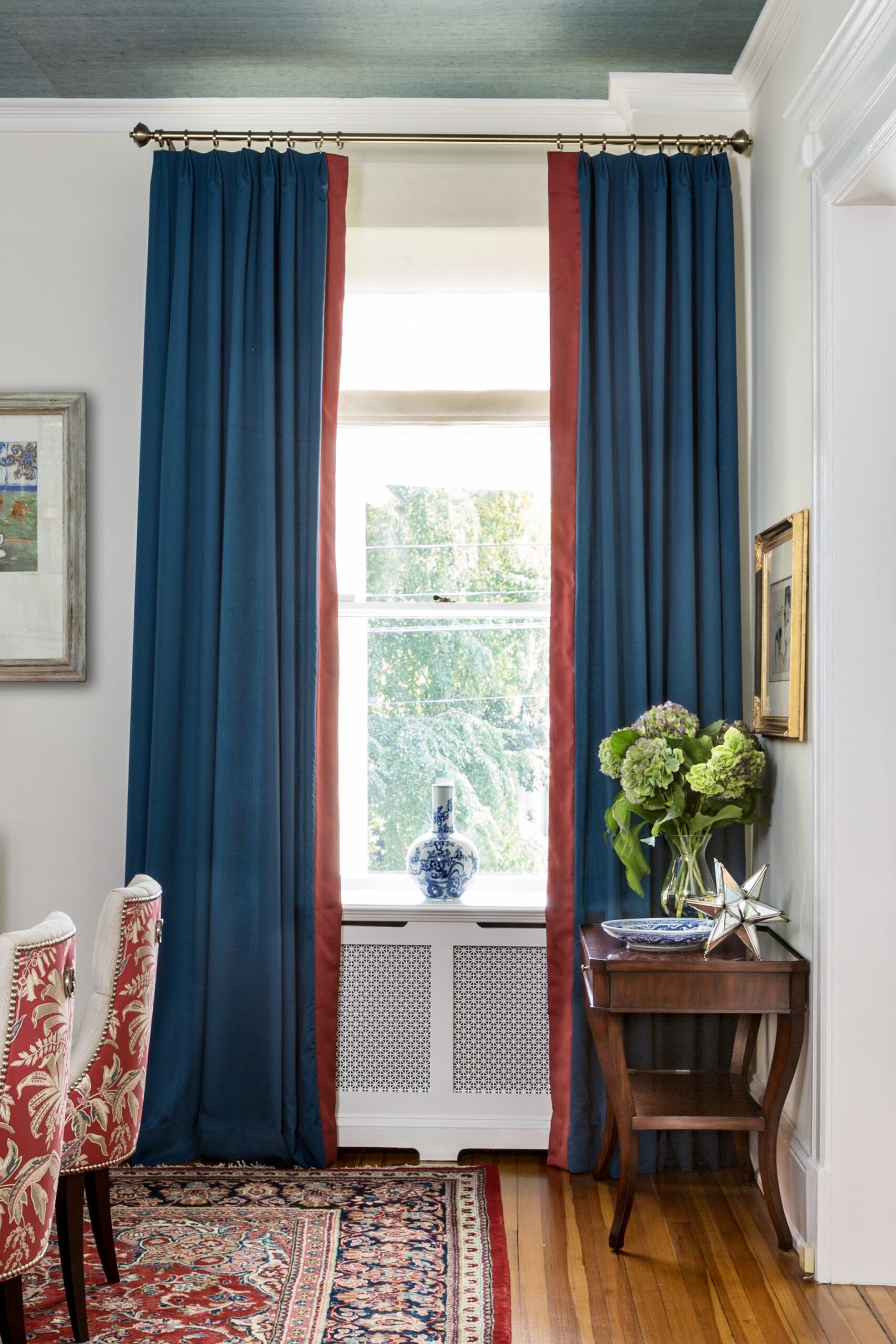 Formal room with full-length navy blue drapes and sheer Roman shade