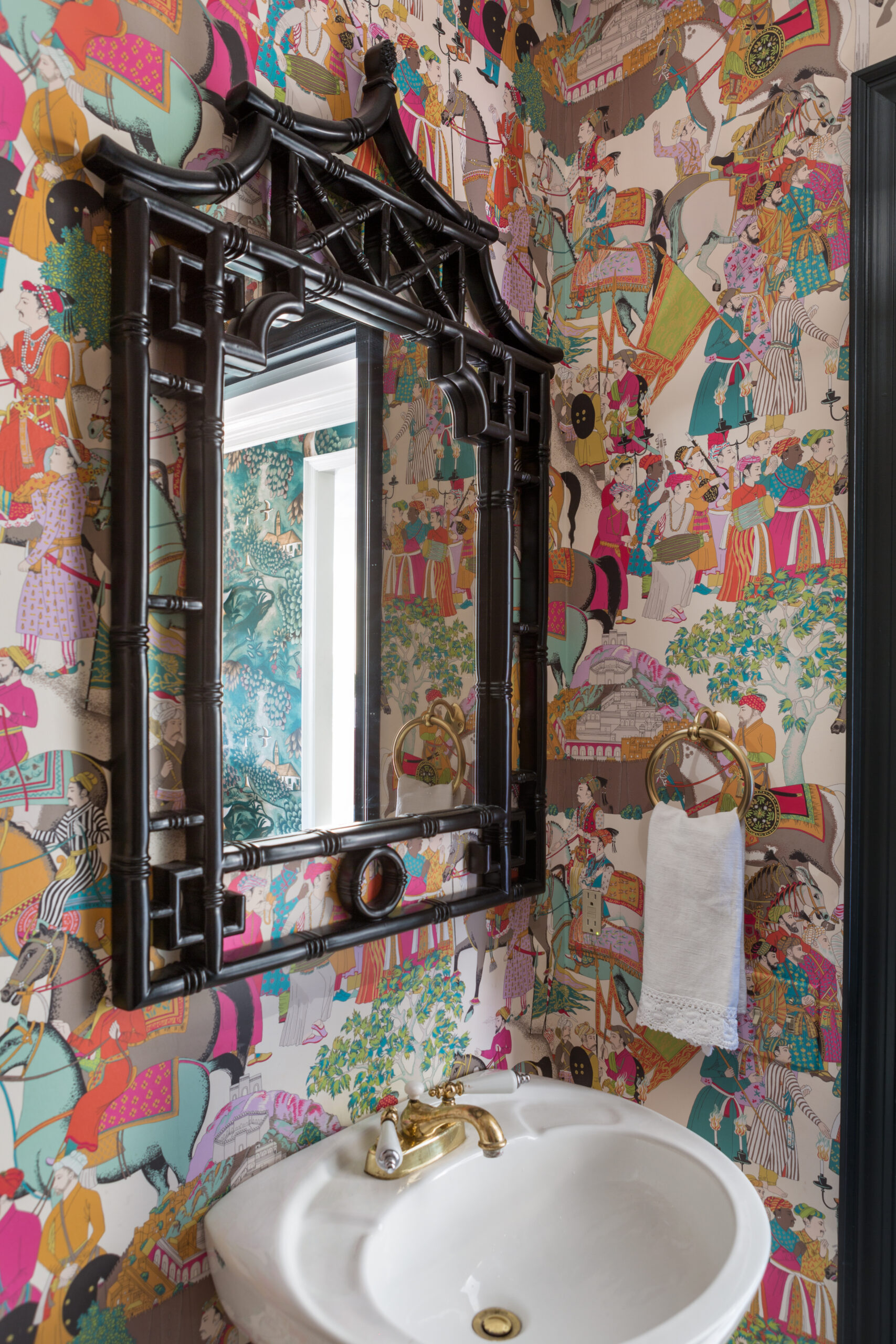 Powder room with mirror and colorful wallpaper.