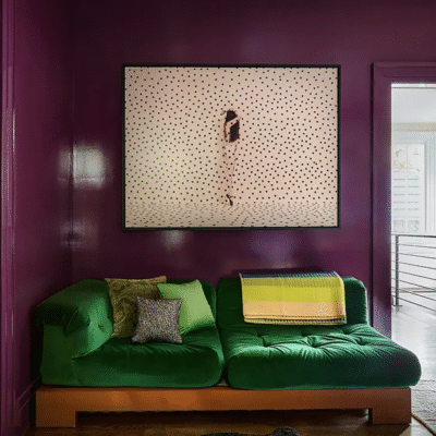 White painting on a purple wall over green sofa