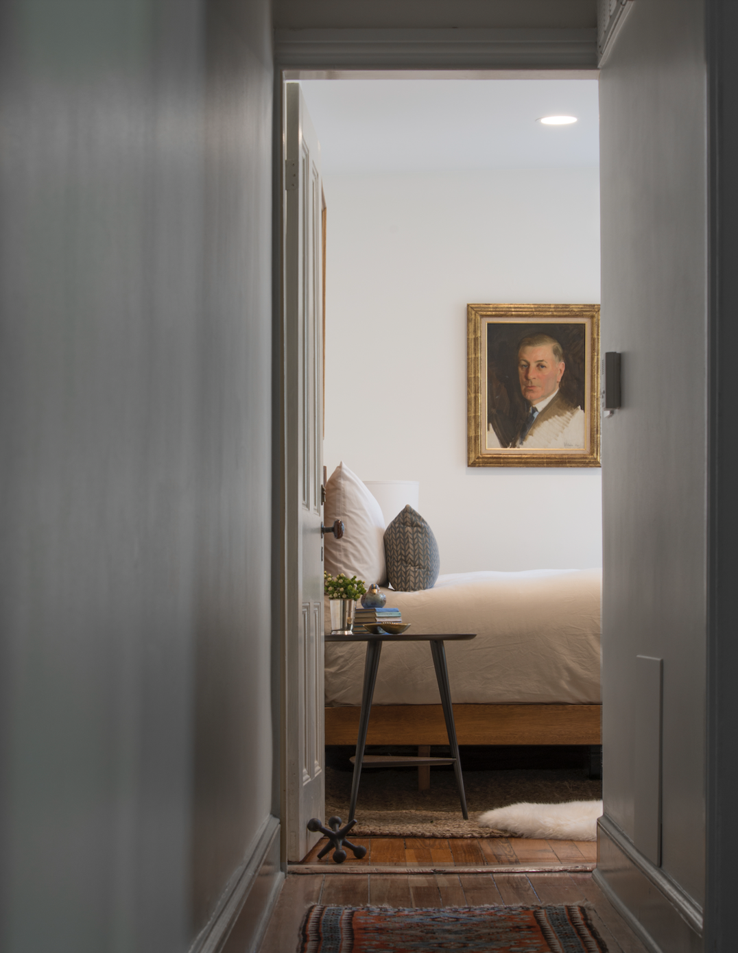 White bedroom at the end of a white hallway