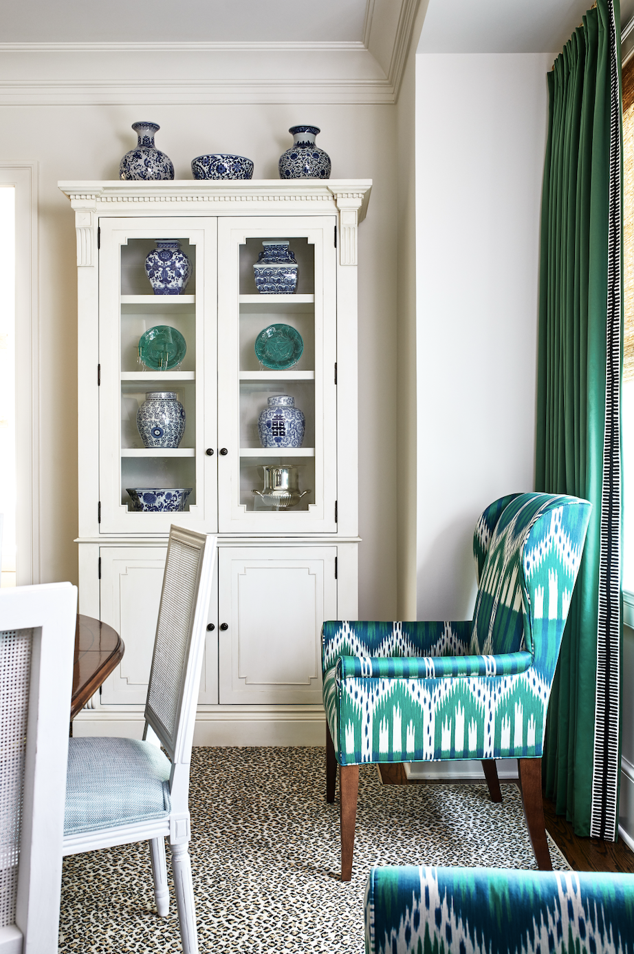 Dining room with white cabinet and chairs and green drapes and host chair