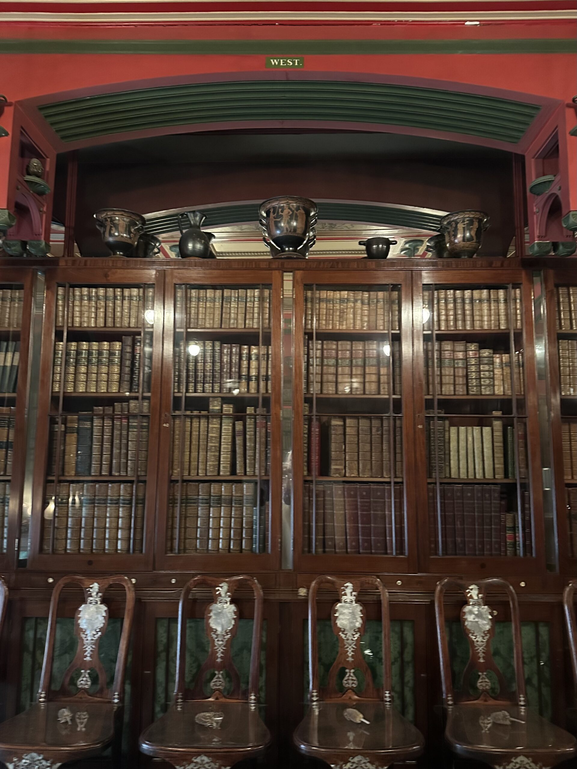 Historic library with vertical mirrors between bookcases and behind arch above.