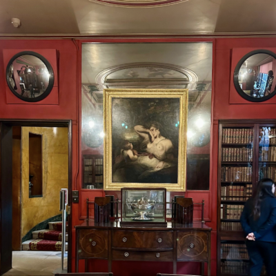 Red 18th-century room with round and rectangular mirrors over a fireplace