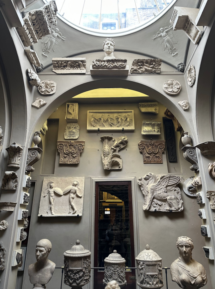 Ancient busts and architectural elements in skylight-lit small museum.