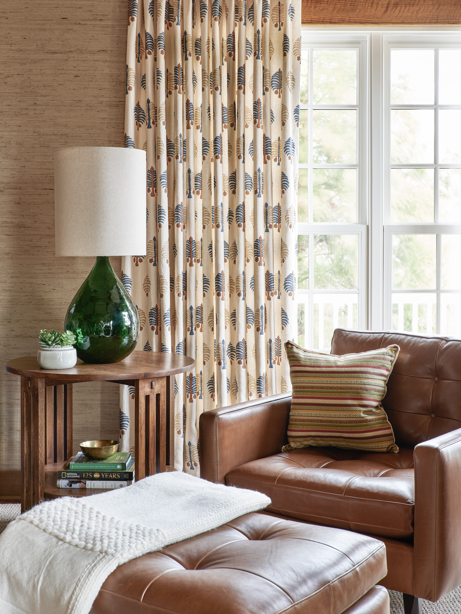 Leather chair and ottoman in front of  green lamp and window with drapes