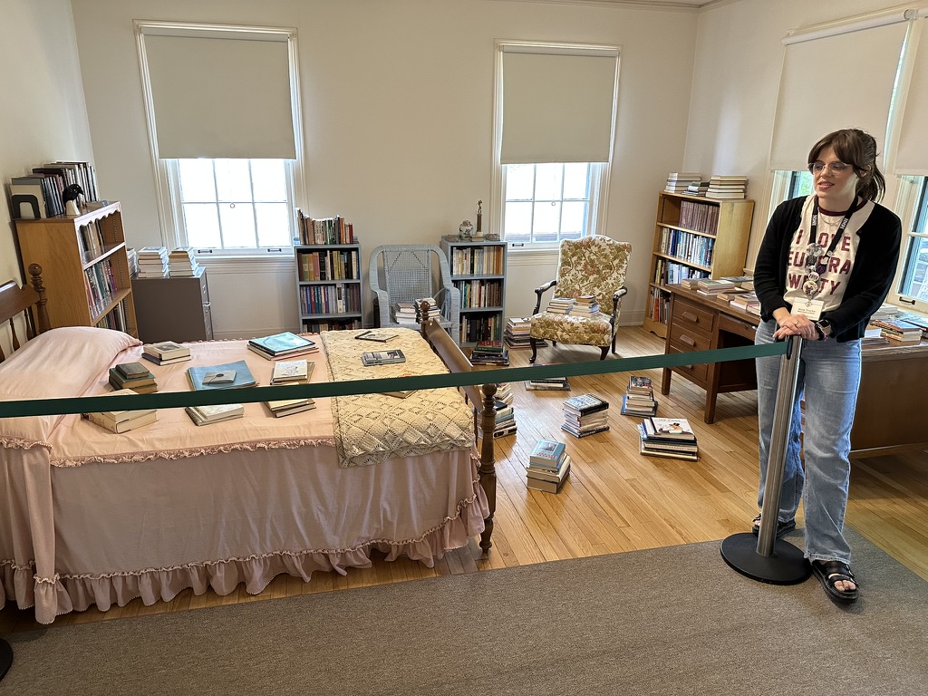 Simple bedroom with piles of books on the floor