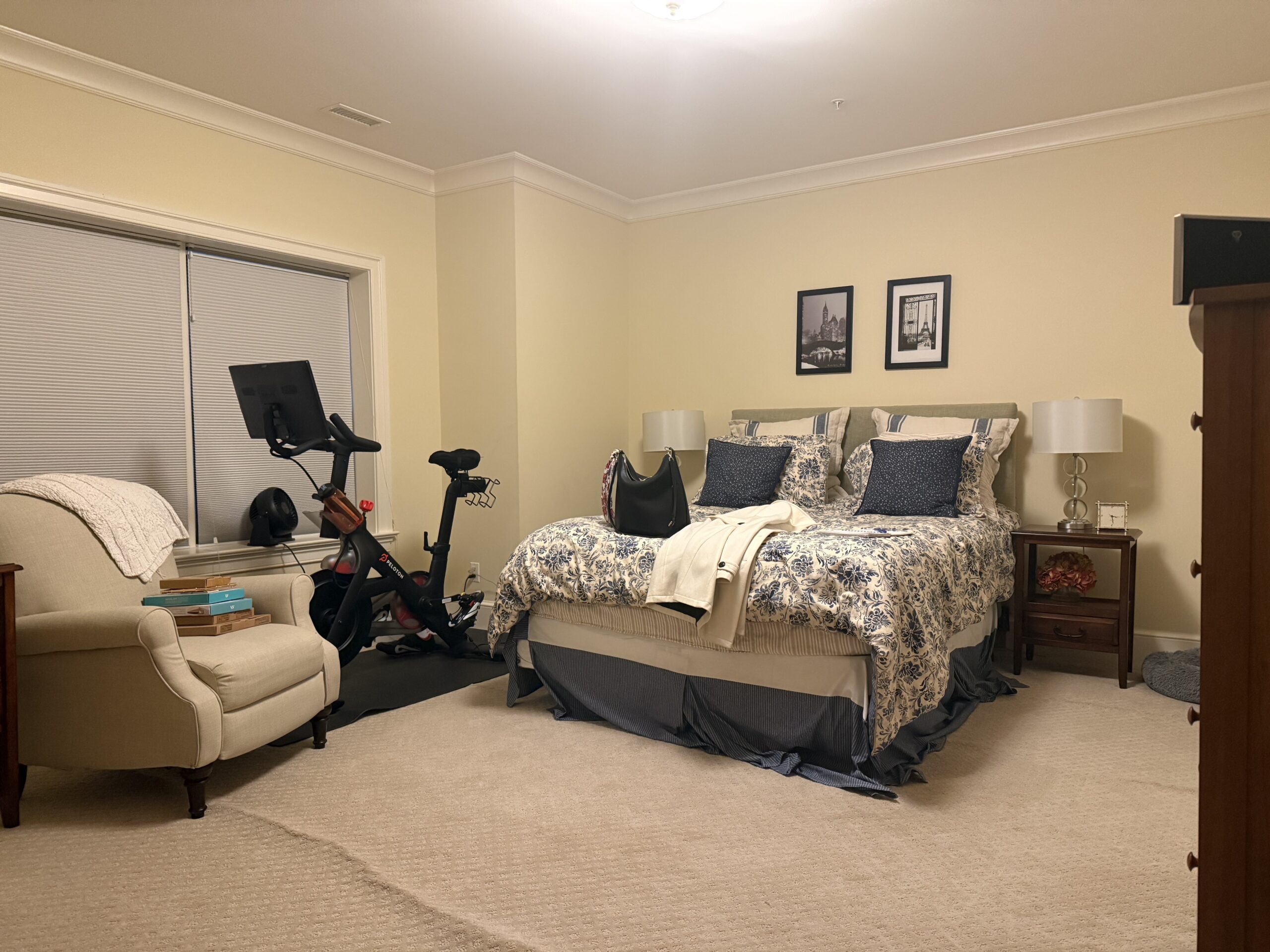 Bed with yellow walls, neutral rug, and beige chair.