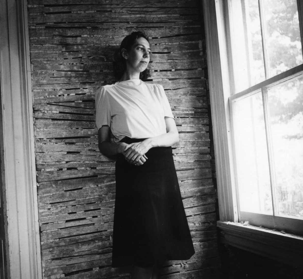 Black and white historic photograph of woman looking out the window