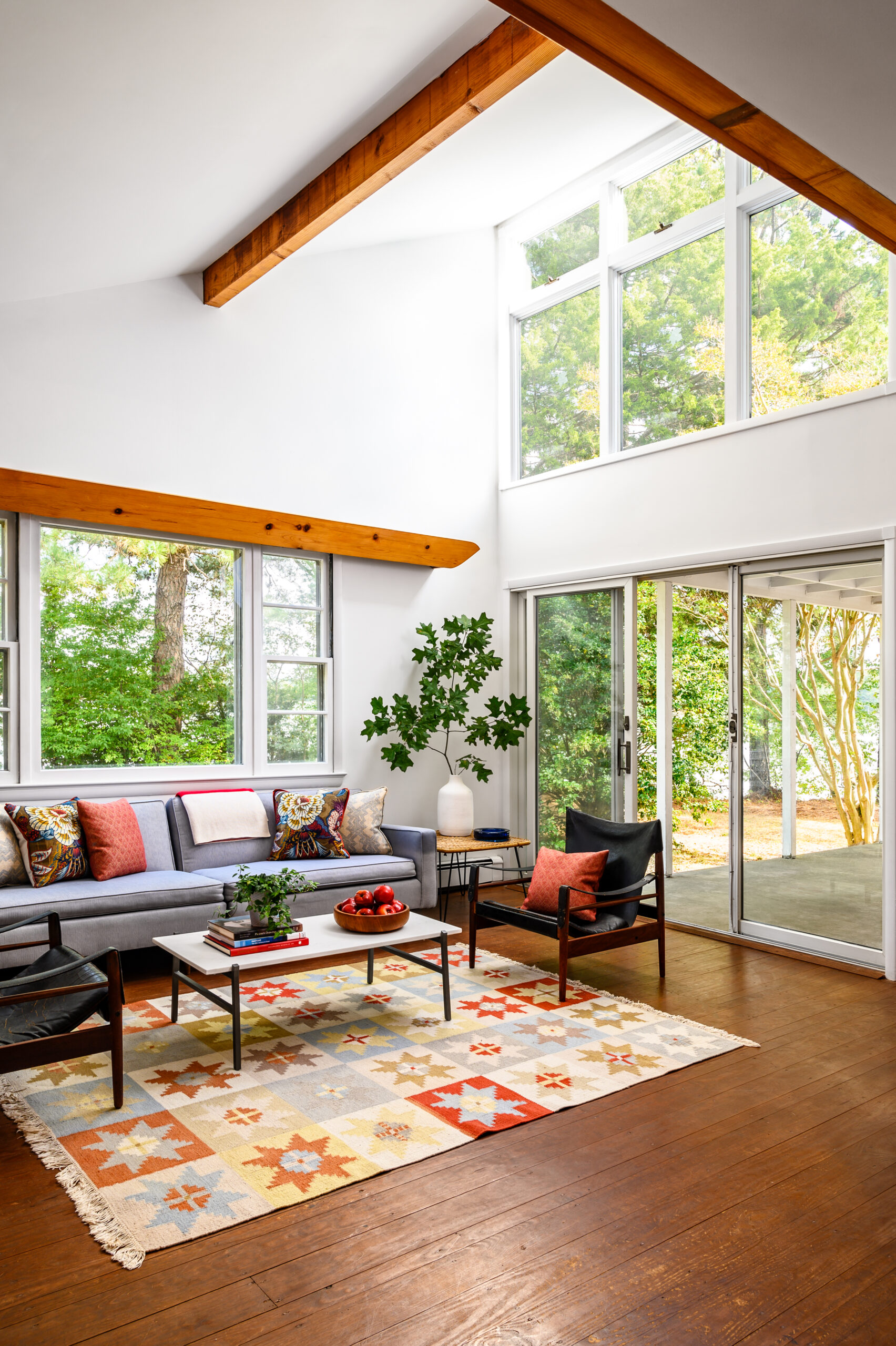 Colorful living room with high ceilings and many windows.