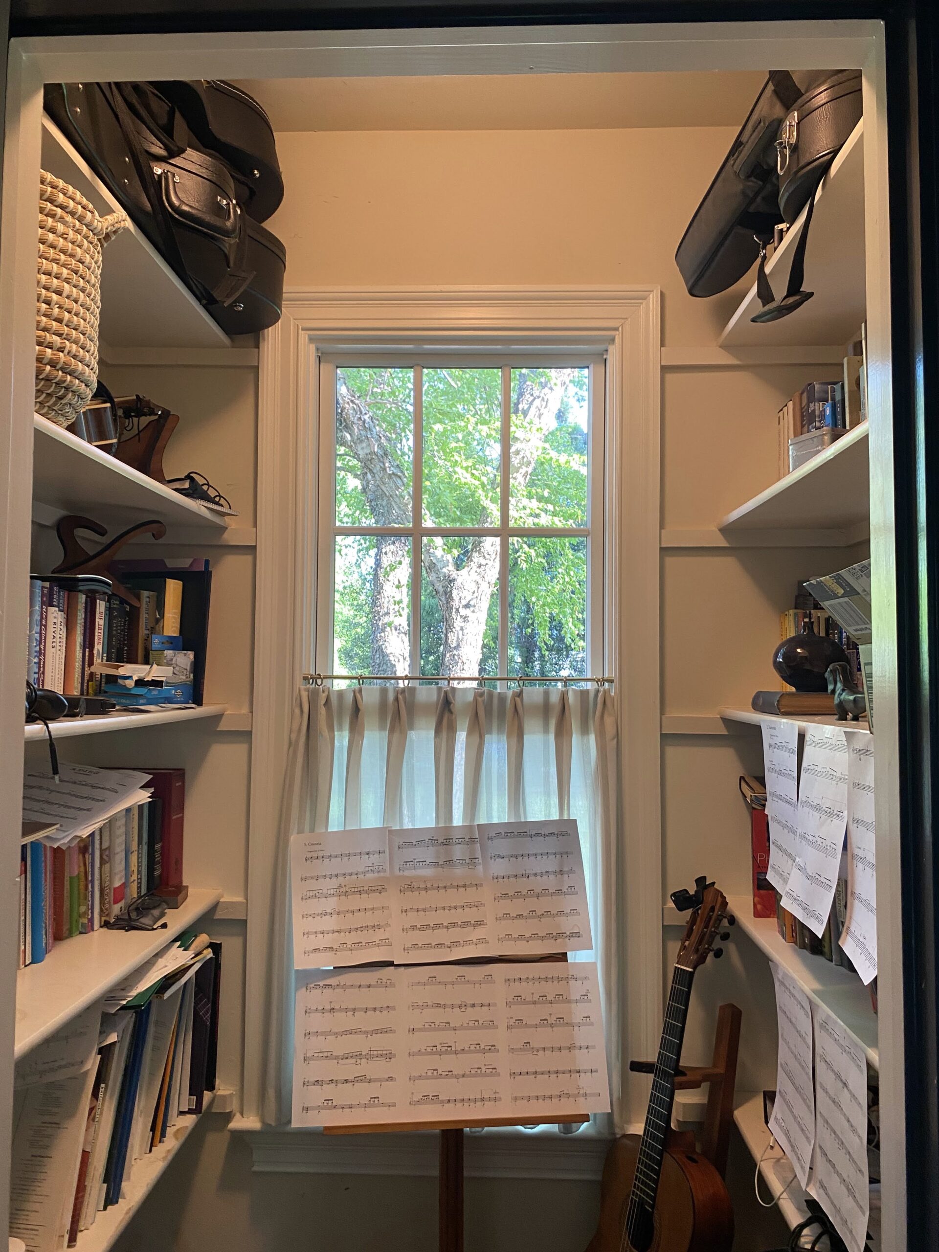 Closet with shelves, sheet music, and a guitar.
