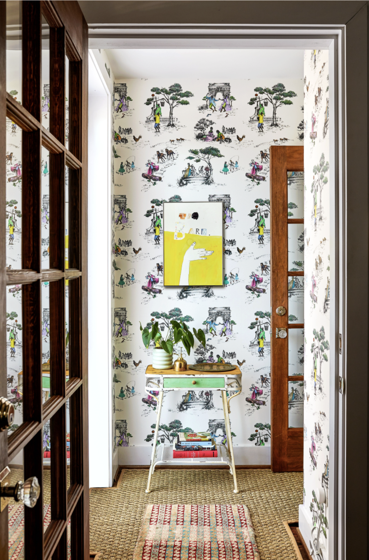 Hallway with layered rugs and whimsical wallpaper.