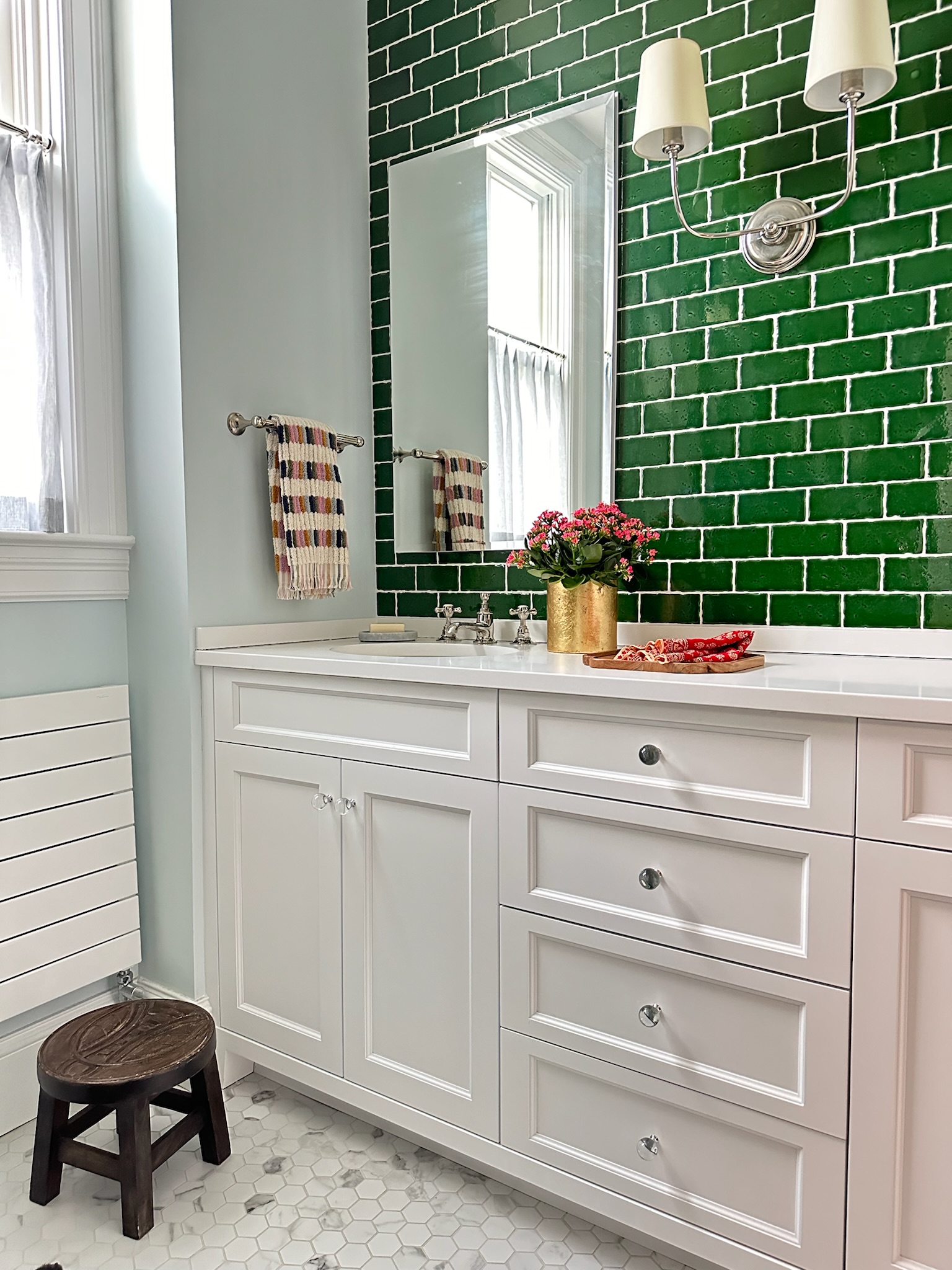 Bathroom with white cabinets, blue walls, and green tile.