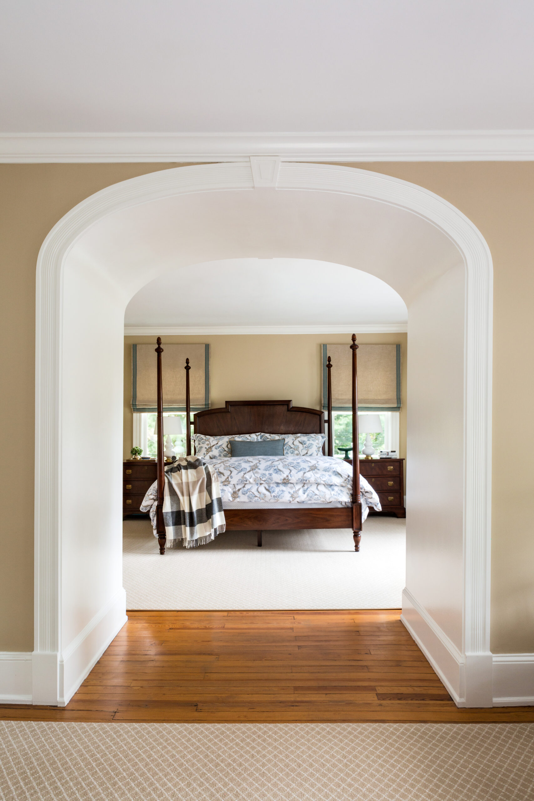 Arched entrance to bedroom with wooden bed and floral bedspread