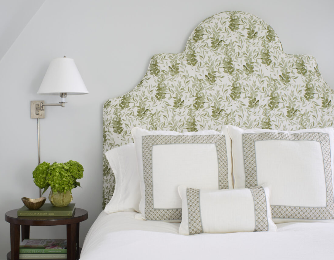 Bed with green and white headboard and wall sconce