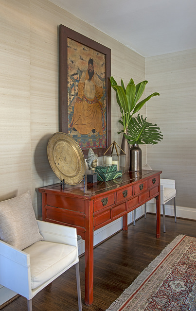 Natural grasscloth wallpaper on walls behind red sideboard.