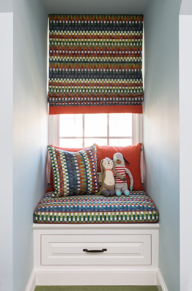Built-in window seat with colorful Roman shade and stuffed animals