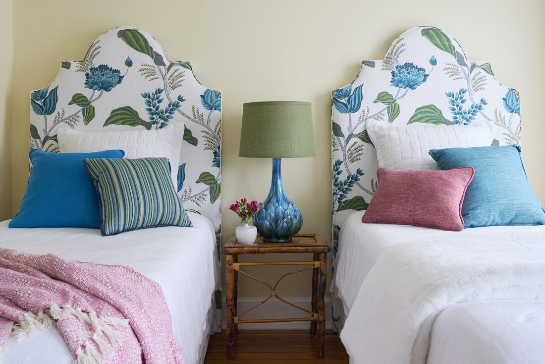 Bedroom with yellow walls and matching twin beds with blue and green floral headboards