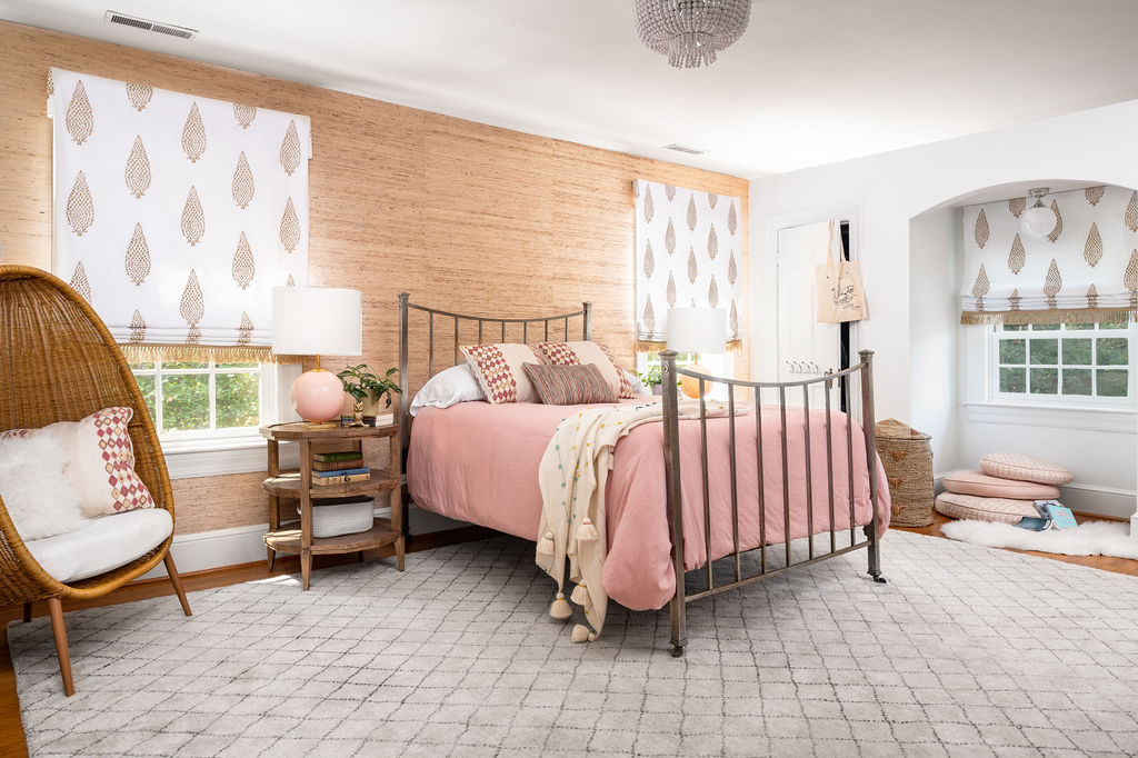 Bedroom with grasscloth, pink bedding, and wicker egg chair