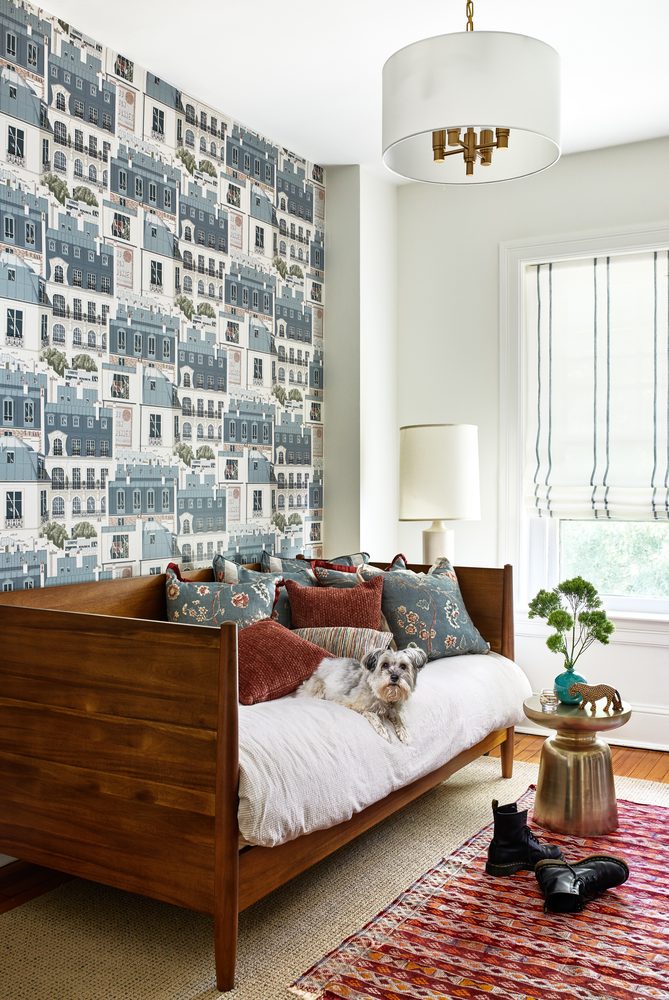 Bedroom with daybed, cityscape wallpaper, striped sheer Roman shade, and dog