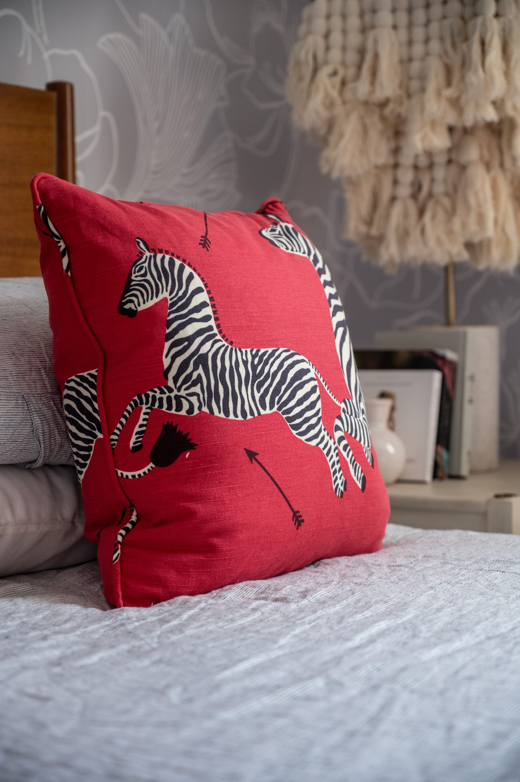 Square red zebra patterned accent pillow in front of two sleeping pillows