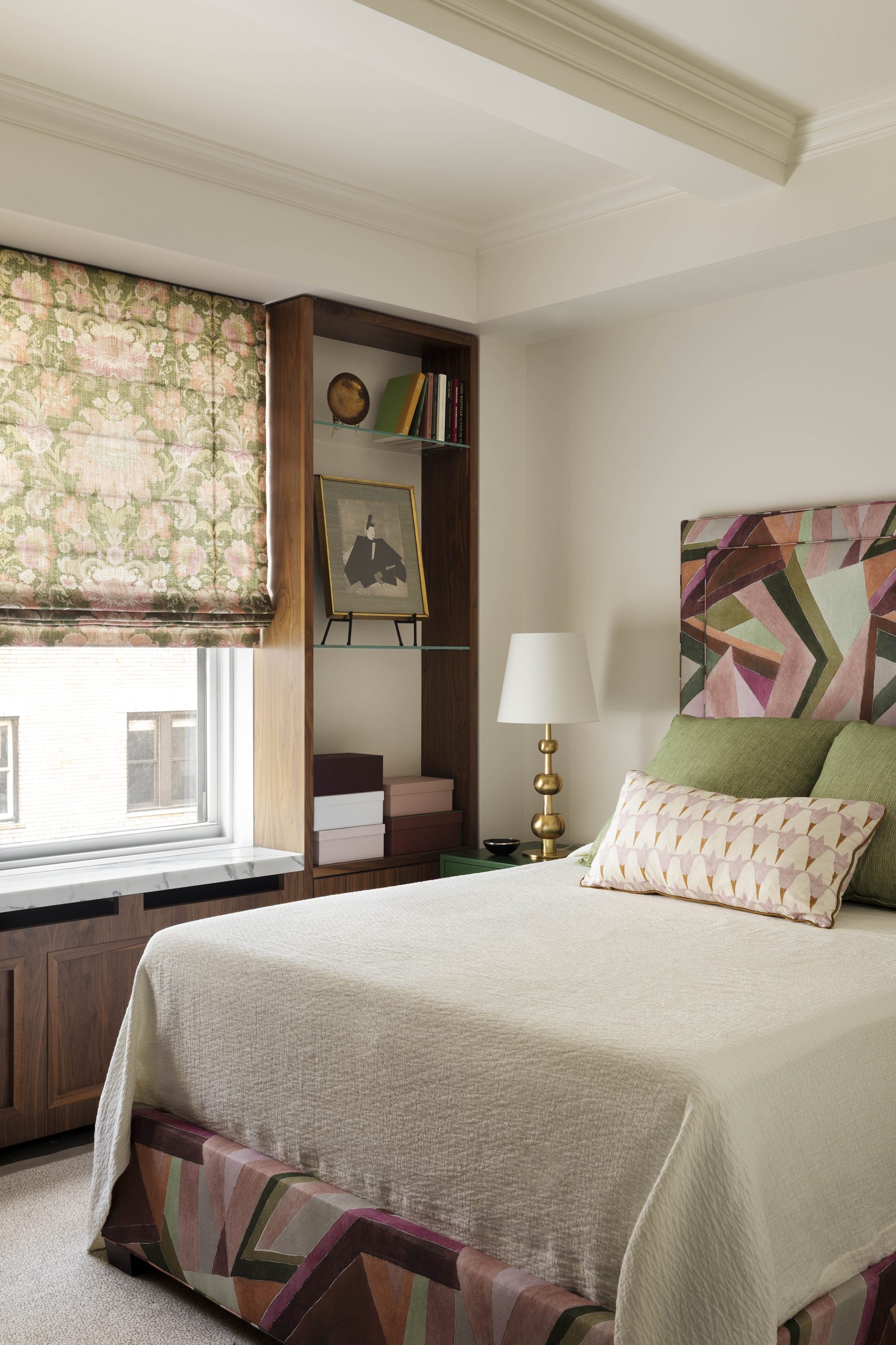 Bed with patterned lumbar pillow in front of green square pillows